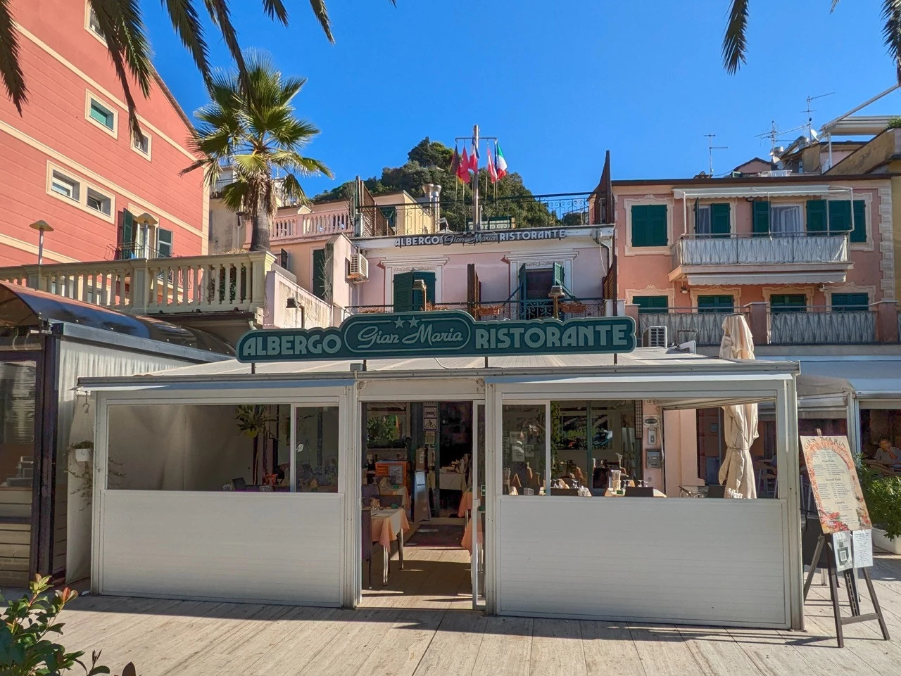 Ingresso dell'Albergo Ristorante Gian Maria nel centro di Moneglia, con insegna visibile e palme sullo sfondo